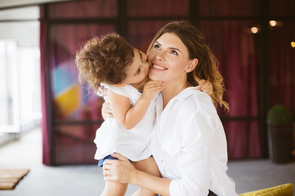 Beautiful young mother in white shirt happily looking aside whil